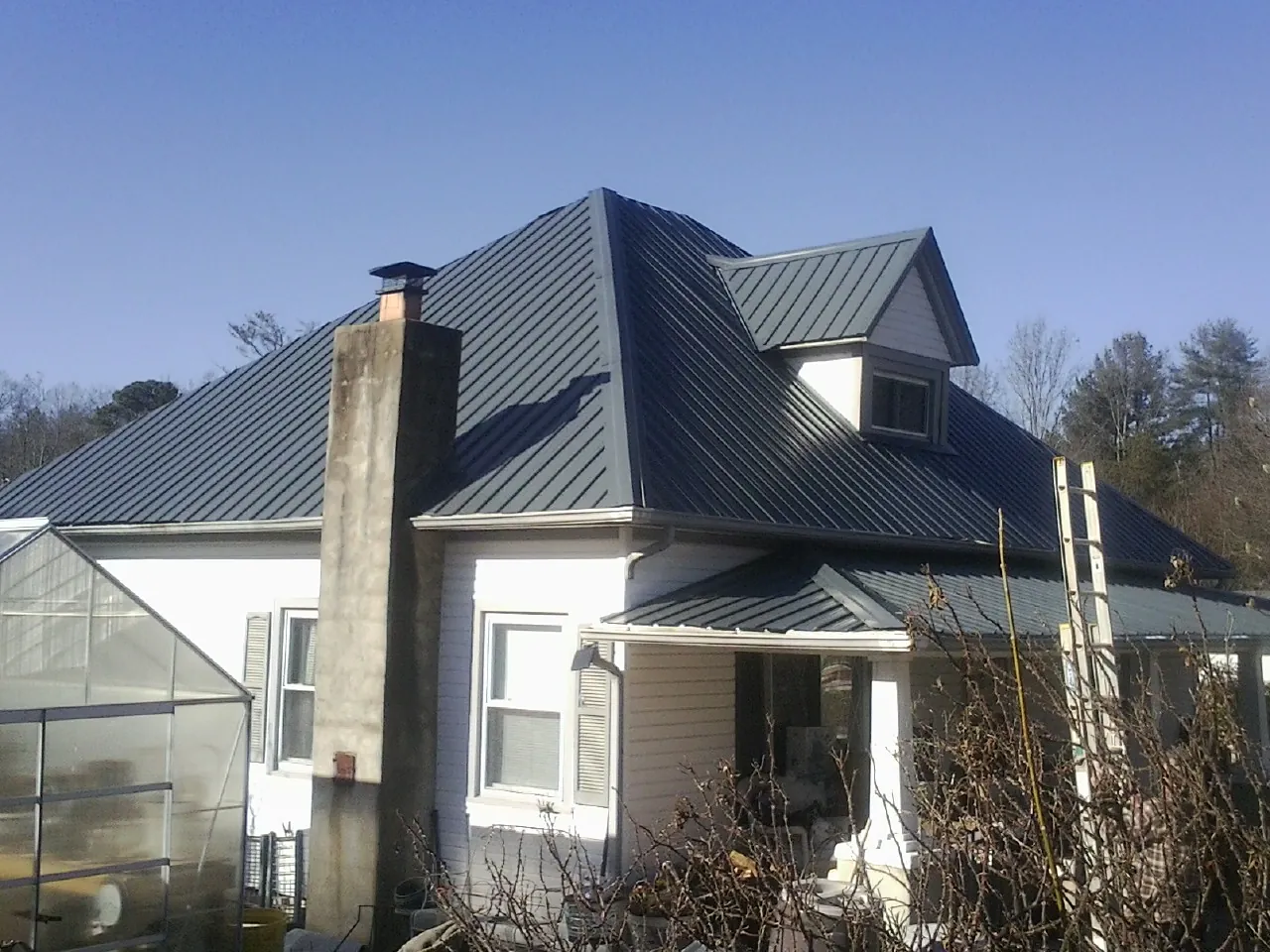 Dark blue standing seam metal roof on a white farmhouse with dormer — Slate & Tile Roof Repair by Roofing Brothers in Mehoopany