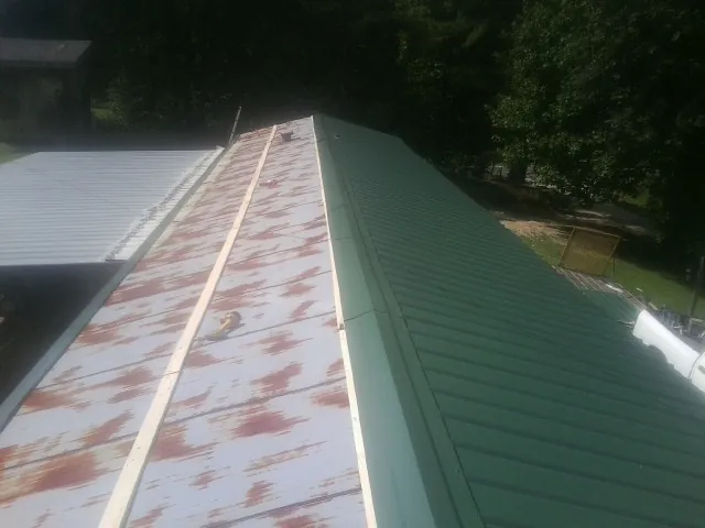 Old rusted panels beside newly installed green metal roofing — Wind Damage Roof Repair by Roofing Brothers in Mehoopany