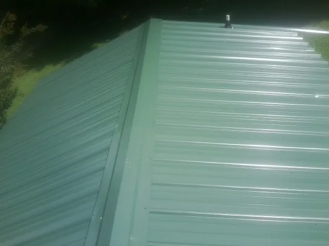 New green metal panels meeting at the ridge of a roof — Flat Roof Repair work by our crew in Mehoopany