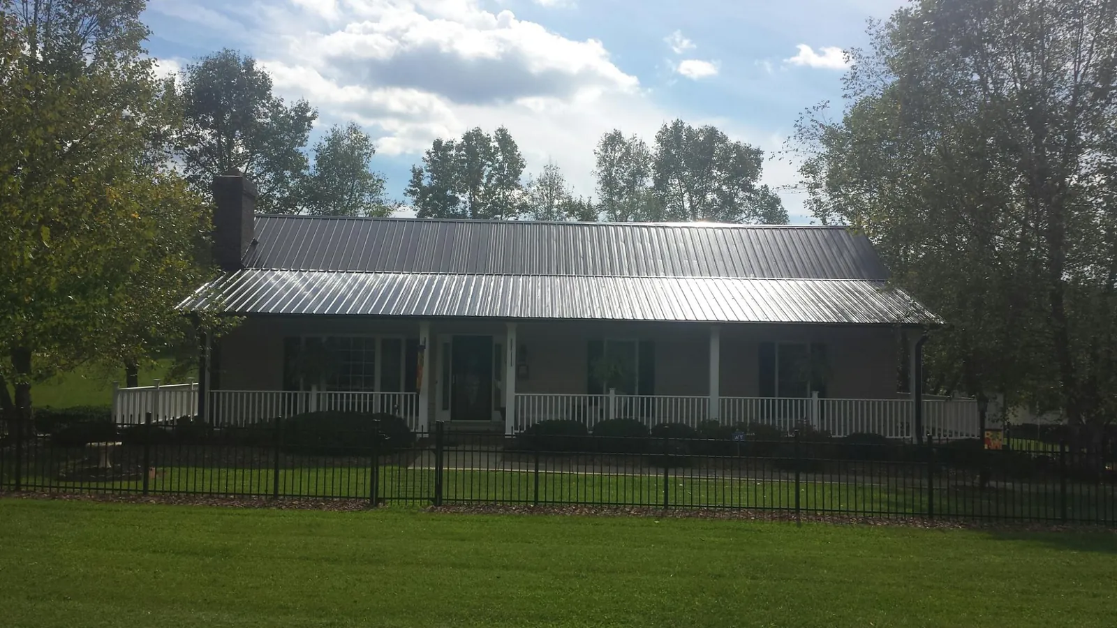 Gray metal roof on a brick ranch with a full width front porch — Gutter Guard Installation work by our crew in Mehoopany