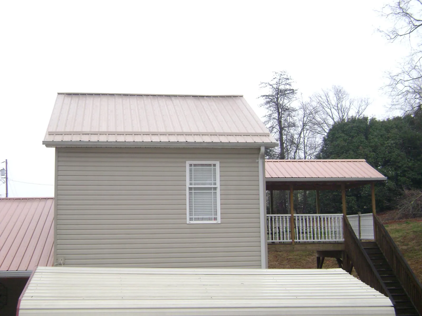 Tan metal roofs on a two story addition and attached porch, from a Roof Replacement job in Mehoopany