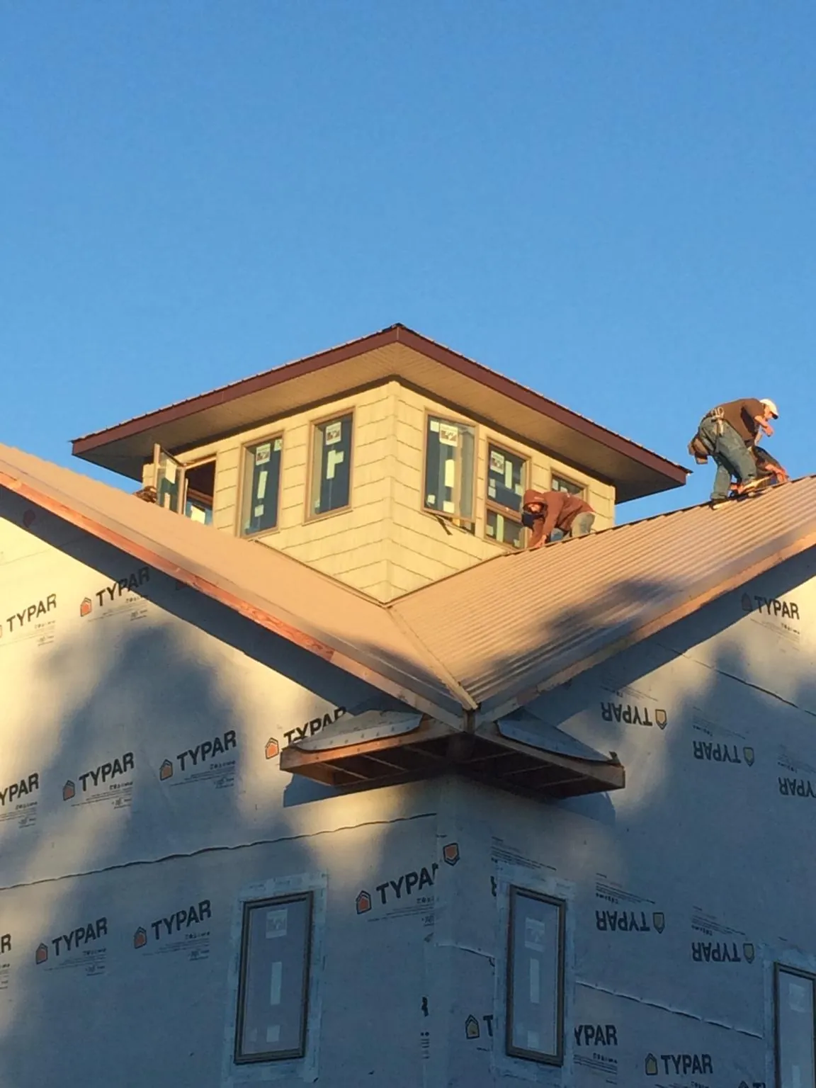 Roofers working around a rooftop cupola on a new metal roof at sunset — Roof Waterproofing in Mehoopany by Roofing Brothers